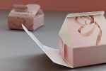 Eine rosa, halbaufgeklappte Faltschachtel mit einer geschlossenen Faltschachtel im Hintergrund.